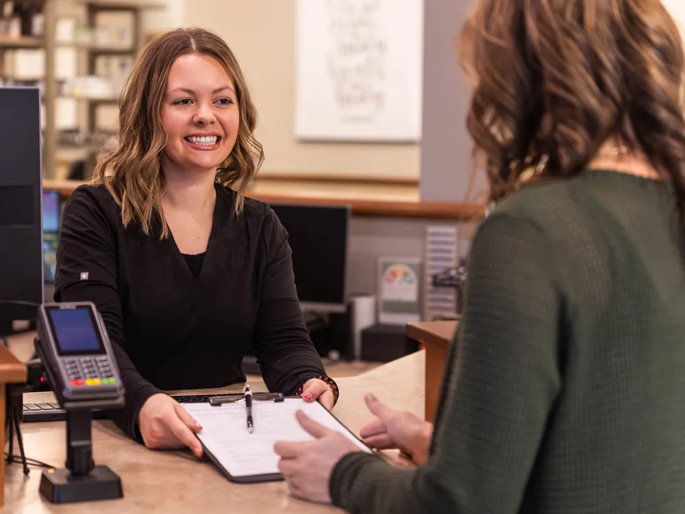 A team member greeting a patient at the Complete Chiropractic front desk