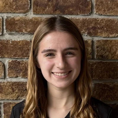 Amelia smiling in front of a brick wall.