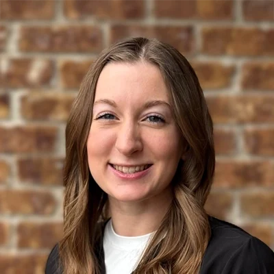 Chiropractic Wooster OH Jaimie Stauffer Jaimie Stauffer smiling in front of a brick wall.